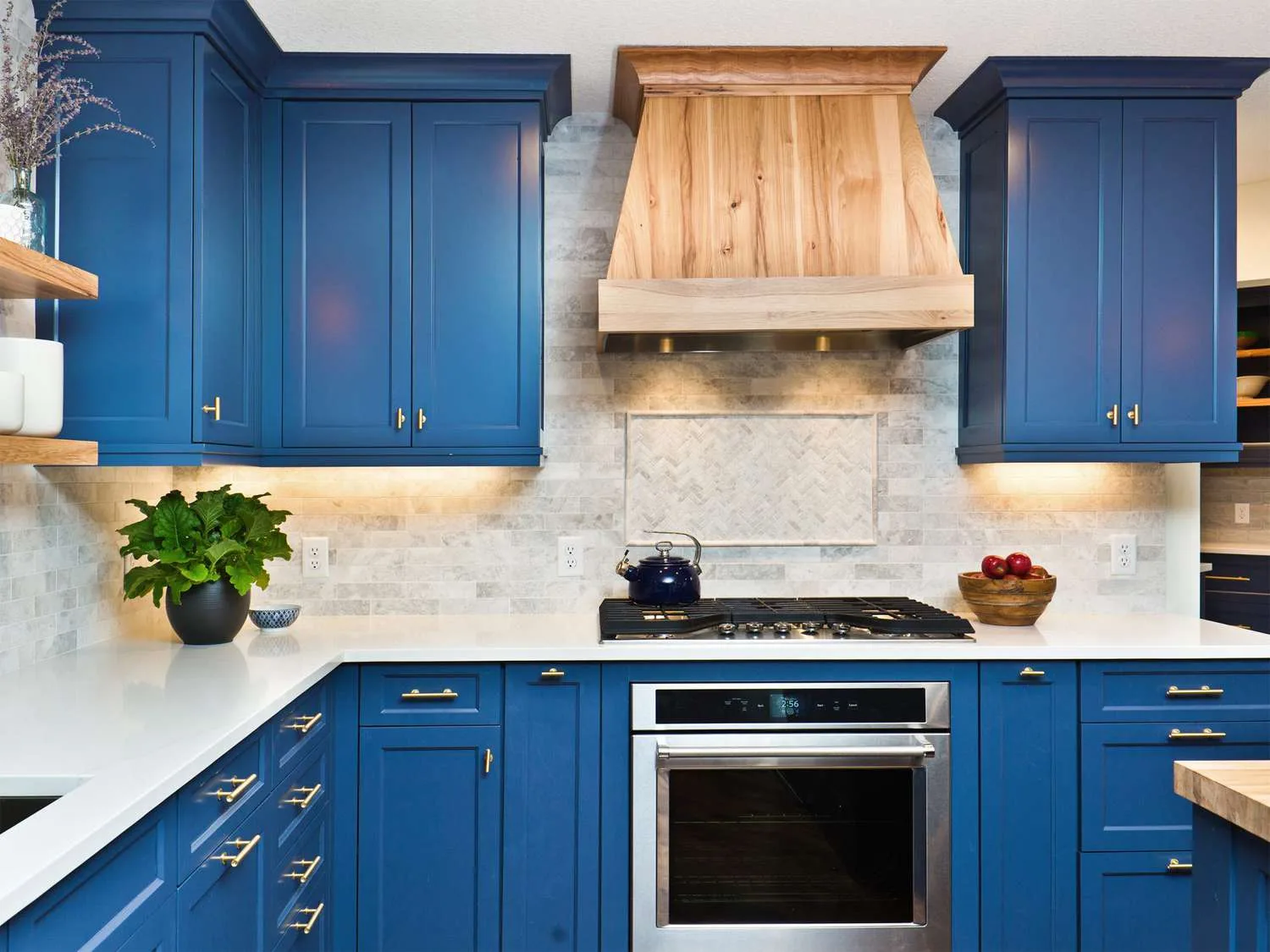Kitchen cabinets freshly painted deep blue with brass hardware and a white countertop