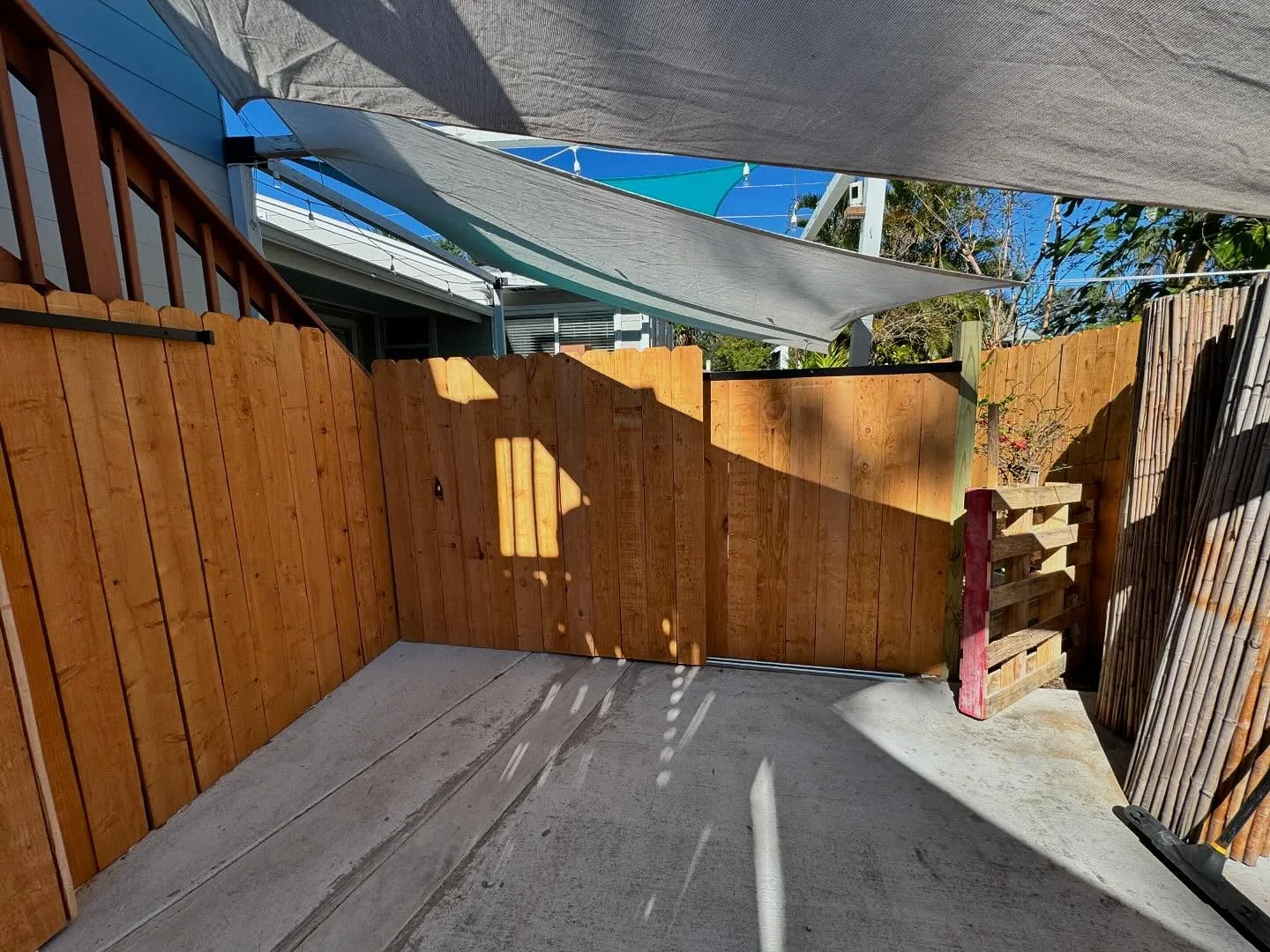 Finished cedar privacy fence running along a driveway with a matching sliding gate closed across the entrance