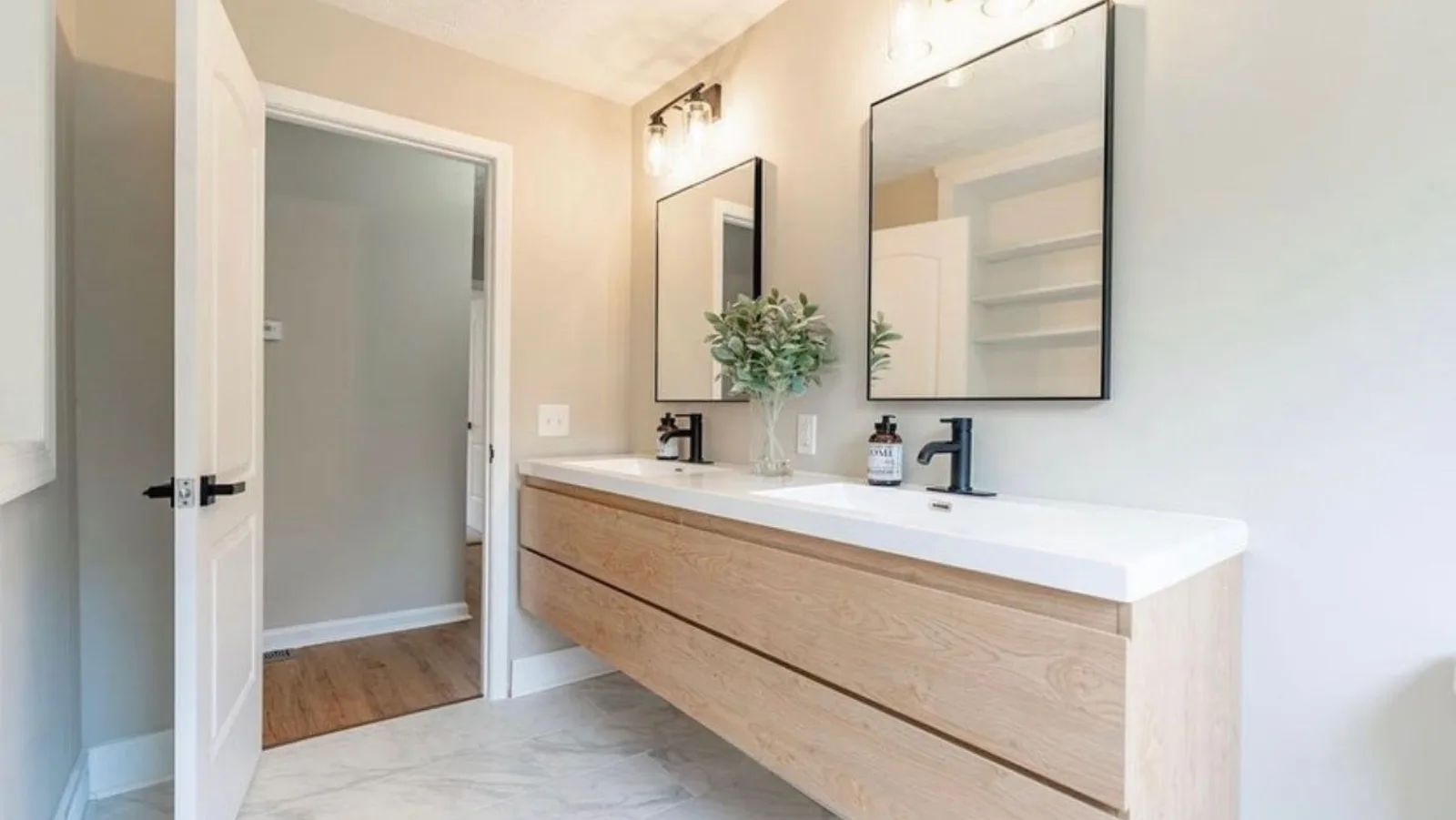 Newly installed floating wood vanity with two sinks, framed mirrors and wall sconces