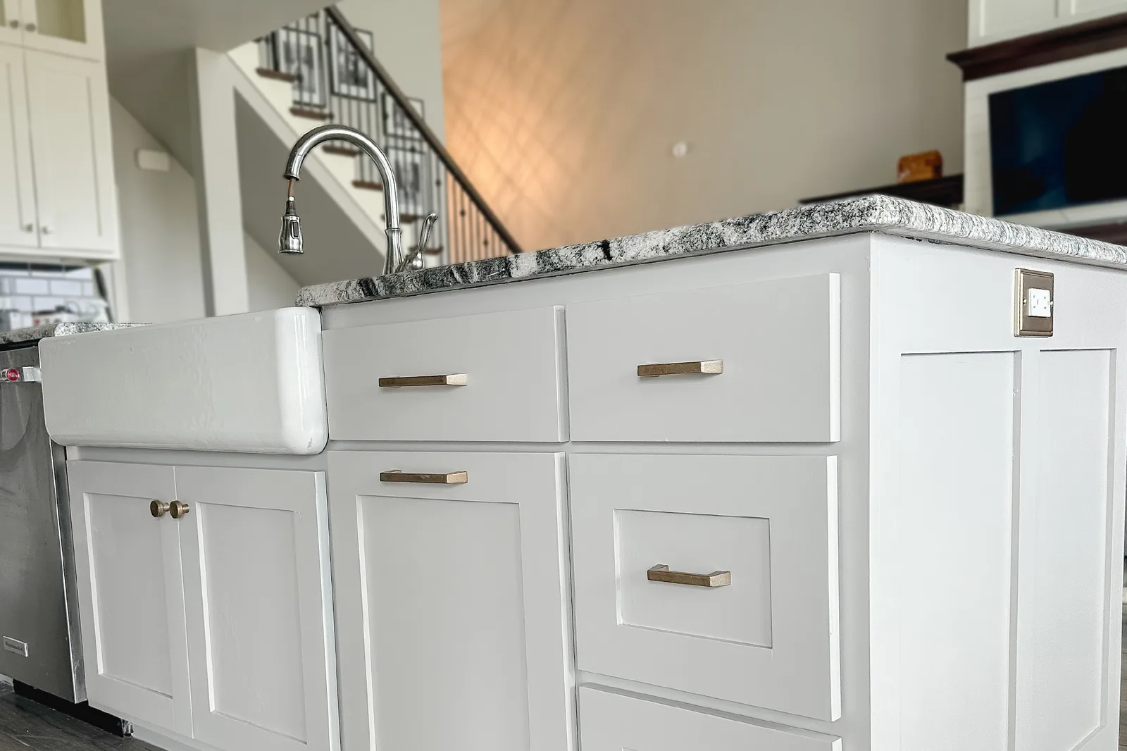 Repainted kitchen island with brass bar pulls, a farmhouse sink and a granite countertop
