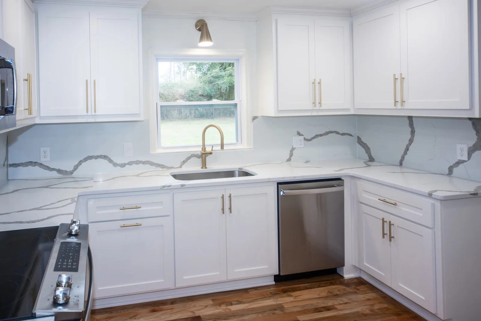 Remodeled kitchen with white shaker cabinets, quartz countertops and a waterfall island